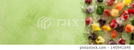 Green background with ice cubes with frozen berries and fruits and mint, banner Green background with ice cubes with frozen berries and fruits and mint, banner 140941846