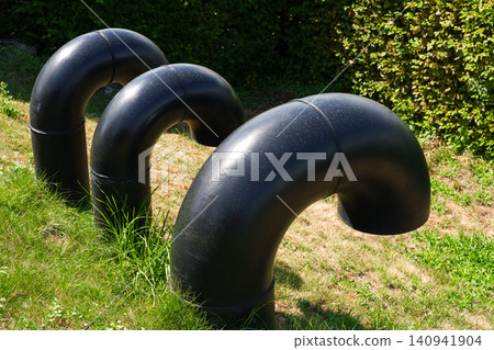 Black curved water pipes on grass near outdoor pool Black curved water pipes on grass near outdoor pool 140941904