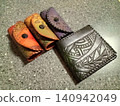 Three leather key cases in different colors and a black leather wallet lined up together. 140942049