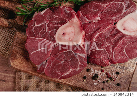 knuckle on the bone, raw meat for ossobuco, on a wooden chopping board, with a sprig of rosemary, and spices, top view, no people, knuckle on the bone, raw meat for ossobuco, on a wooden chopping board, with a sprig of rosemary, and spices, top view, no people, 140942314
