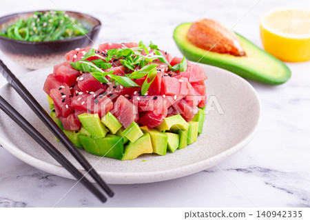 Fresh tuna tartare with avocado served on a marble table with soy sauce and seaweed salad Fresh tuna tartare with avocado served on a marble table with soy sauce and seaweed salad 140942335
