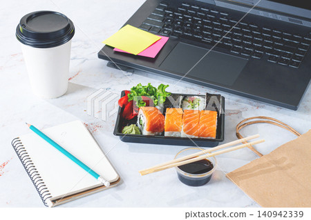 Lunch break with sushi and workspace setup in a modern office environment around midday,no people Lunch break with sushi and workspace setup in a modern office environment around midday,no people 140942339
