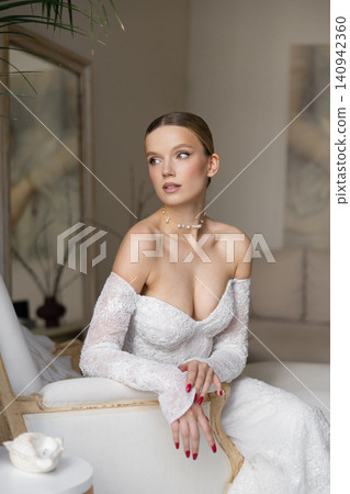 Elegant bride in white long dress posing on chaise lounge 140942360