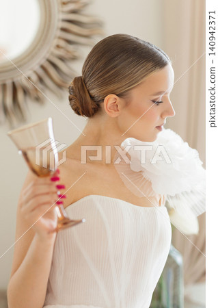 Young woman celebrating in elegant white dress and holding glass Young woman celebrating in elegant white dress and holding glass 140942371