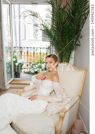 Bride sitting on couch wearing elegant wedding dress Bride sitting on couch wearing elegant wedding dress 140942383