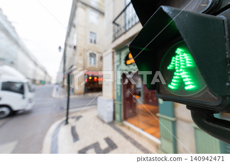 Green pedestrian signal shows it is safe to cross the street at a busy intersection in a city on a rainy day Green pedestrian signal shows it is safe to cross the street at a busy intersection in a city on a rainy day 140942471