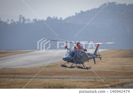 Helicopter taking off from runway with mountain background 140942474