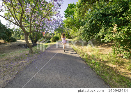 Walking on a path surrounded by trees and flowers in a park during a sunny day in spring Walking on a path surrounded by trees and flowers in a park during a sunny day in spring 140942484