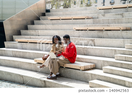 Nerdy african american man student helping black female friend with studies, explaining work process Nerdy african american man student helping black female friend with studies, explaining work process 140942563