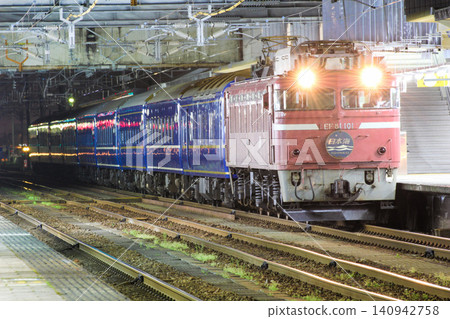 The sleeper express "Nihonkai," pulled by EF81 type rose pink (JNR livery) locomotive No. 101, stops at Takaoka Station at night. The sleeper express "Nihonkai," pulled by EF81 type rose pink (JNR livery) locomotive No. 101, stops at Takaoka Station at night. 140942758