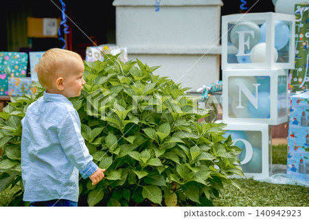 a boy in a blue shirt celebrates his 1 year anniversary, there are cubes with the letters ONE. High quality photo a boy in a blue shirt celebrates his 1 year anniversary, there are cubes with the letters ONE. High quality photo 140942923