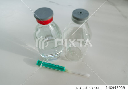 Two glass medical bottles of table salt and syringe. High quality photo Two glass medical bottles of table salt and syringe. High quality photo 140942939
