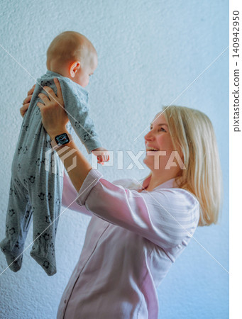 A European mother holds a 5-month-old boy in her outstretched arms High quality photo A European mother holds a 5-month-old boy in her outstretched arms High quality photo 140942950