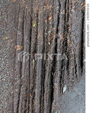 Tire tracks left on a muddy road after rain | Texture background material that expresses nature and driving traces Tire tracks left on a muddy road after rain | Texture background material that expresses nature and driving traces 140943016