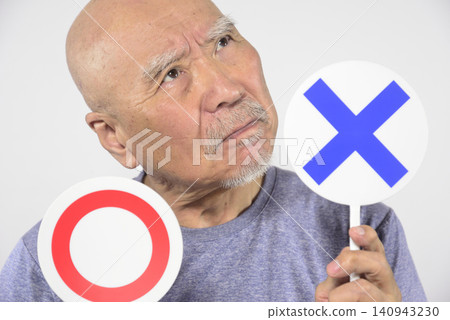 An elderly person holding a ○× plate 140943230
