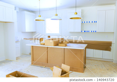 Workers are setting up new cabinets countertops in kitchen area is filled with boxes, packing materials. Workers are setting up new cabinets countertops in kitchen area is filled with boxes, packing materials. 140943720