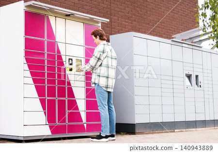 man uses a self-service terminal at a bright parcel locker for parcel pickup. Enjoying convenient ecommerce online shopping with fast contactless delivery technology 140943889