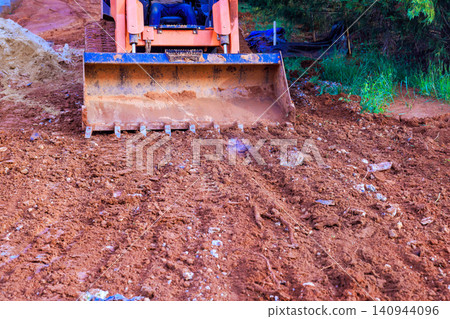 Bulldozer works on ground at construction site it pushes dirt to level area for future building. Bulldozer works on ground at construction site it pushes dirt to level area for future building. 140944096