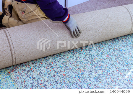 Contractor is laying down carpet on floor of room preparation for installation work. Contractor is laying down carpet on floor of room preparation for installation work. 140944099