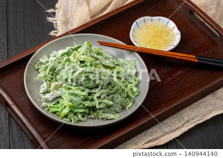 Traditional Chinese steamed flour coated celery leaves in ceramic bowl with garlic dip 140944140