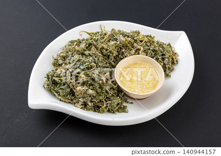 Traditional Chinese steamed flour coated dandelion greens on porcelain plate with chopsticks Traditional Chinese steamed flour coated dandelion greens on porcelain plate with chopsticks 140944157