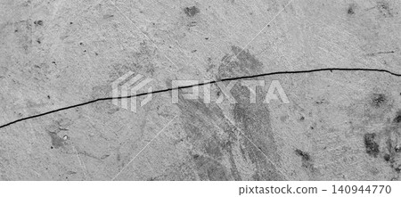 The gray concrete wall surface reveals long horizontal cracks and a natural cement texture that appears weathered. The gray concrete wall surface reveals long horizontal cracks and a natural cement texture that appears weathered. 140944770