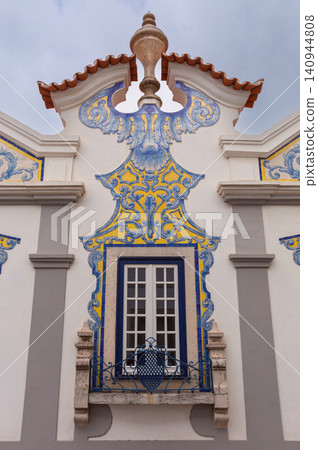 Close-up of an ornate blue and yellow azulejo tile panel framing a window on a historic Portuguese house in Cascais, Portugal. 140944808