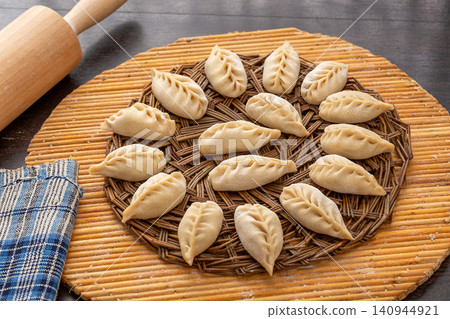 raw handmade Chinese steamed dumplings, unbaked leaf shaped Jiaozi with flour dust, traditional food preparation raw handmade Chinese steamed dumplings, unbaked leaf shaped Jiaozi with flour dust, traditional food preparation 140944921