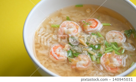 rice soup with shrimp in white bowl on yellow background rice soup with shrimp in white bowl on yellow background 140945031