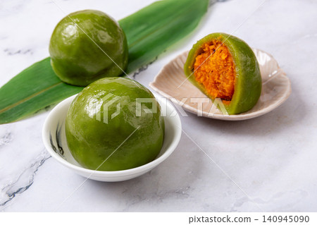 traditional green rice balls with salted egg yolk and pork floss filling, savory Qingtuan mochi on bamboo mat traditional green rice balls with salted egg yolk and pork floss filling, savory Qingtuan mochi on bamboo mat 140945090
