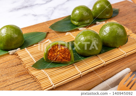 traditional green rice balls with salted egg yolk and pork floss filling, savory Qingtuan mochi on bamboo mat traditional green rice balls with salted egg yolk and pork floss filling, savory Qingtuan mochi on bamboo mat 140945092