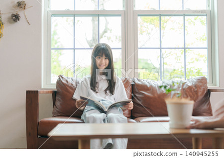 一個孩子坐在沙發上看書。 一個孩子坐在沙發上看書。 140945255