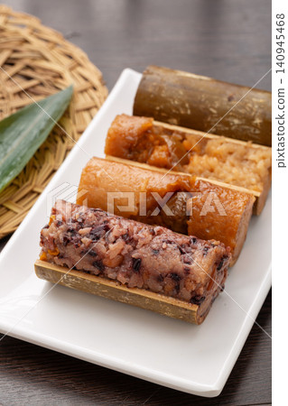 assortment of steamed sweet and savory zongzi dumplings featuring red bean, purple rice, and meat flavors. 140945468