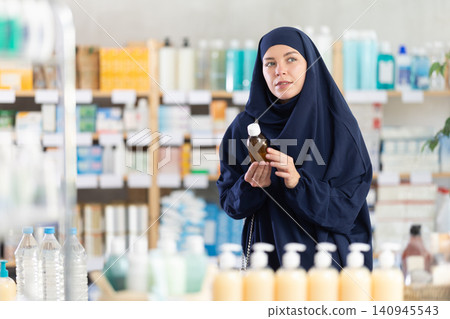 Young Muslim woman choosing cough syrup at pharmacy Young Muslim woman choosing cough syrup at pharmacy 140945543