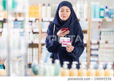 Muslim woman scanning barcode on paracetamol box with phone at pharmacy Muslim woman scanning barcode on paracetamol box with phone at pharmacy 140945556