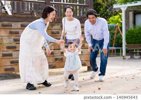 一家三代人看著他們的孩子在公園裡踏出人生的第一步。 一家三代人看著他們的孩子在公園裡踏出人生的第一步。 140945643
