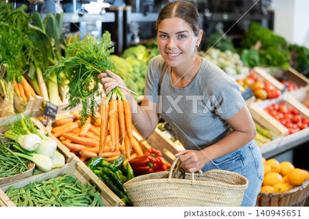 Young girl purchaser buying organic carrot in grocery store Young girl purchaser buying organic carrot in grocery store 140945651