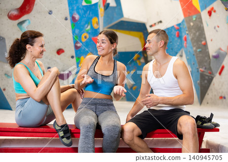 Young man and two women talking merrily sitting in climbing hangar 140945705