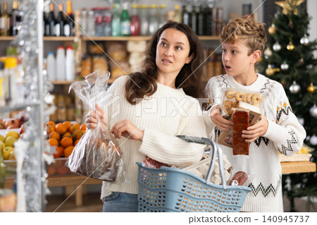 Adolescence boy with mother choose consider snacks in shop on eve of New Year 140945737