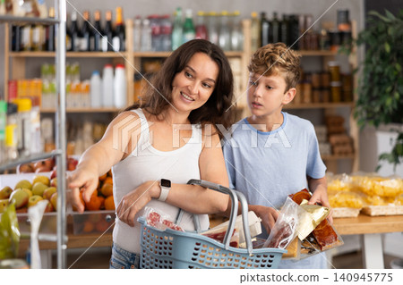Teenage son and mother choose different products together in grocery supermarket Teenage son and mother choose different products together in grocery supermarket 140945775