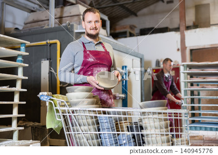 Smiling artisan proudly showcasing collection of ceramic plates Smiling artisan proudly showcasing collection of ceramic plates 140945776