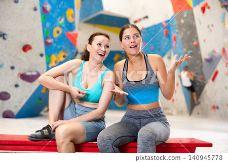 Rest after rock climbing - two friends exchange impressions about training at climbing wall Rest after rock climbing - two friends exchange impressions about training at climbing wall 140945778