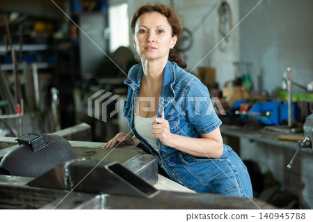 Portrait of confident female worker in workshop of metallurgical plant Portrait of confident female worker in workshop of metallurgical plant 140945788