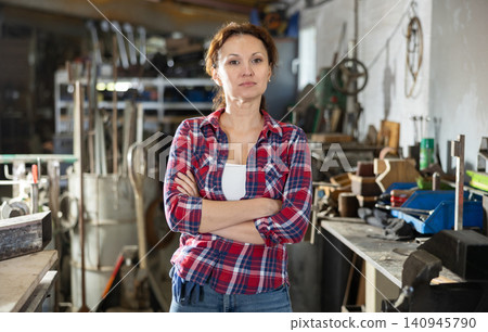 Female employee of workshop stands next to vise, resting from labors Female employee of workshop stands next to vise, resting from labors 140945790