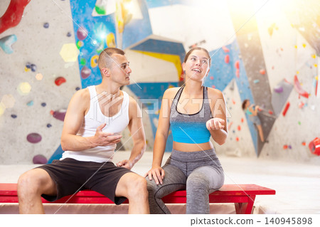 Young man and woman talking merrily sitting in climbing hangar Young man and woman talking merrily sitting in climbing hangar 140945898