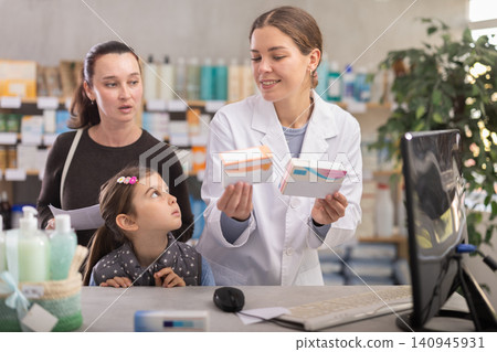 Pharmacist helping woman with girl choose medications at pharmacy Pharmacist helping woman with girl choose medications at pharmacy 140945931