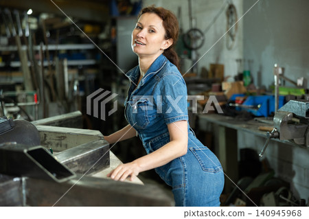Woman employee of carpentry workshop took time out from work, stands resting Woman employee of carpentry workshop took time out from work, stands resting 140945968