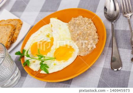 Fried eggs served with oatmeal for breakfast Fried eggs served with oatmeal for breakfast 140945973