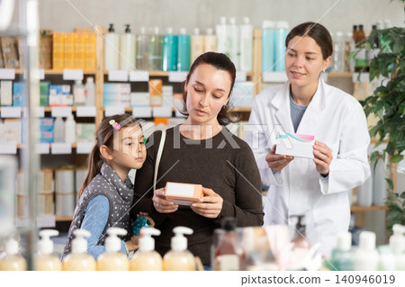 Middle-aged woman with daughter choosing pills in drugstore Middle-aged woman with daughter choosing pills in drugstore 140946019