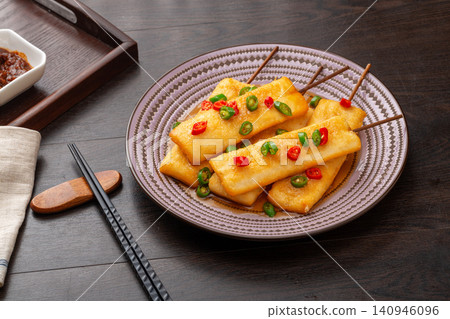 fried rice cake skewers seasoned with sliced red and green chili peppers. fried rice cake skewers seasoned with sliced red and green chili peppers. 140946096